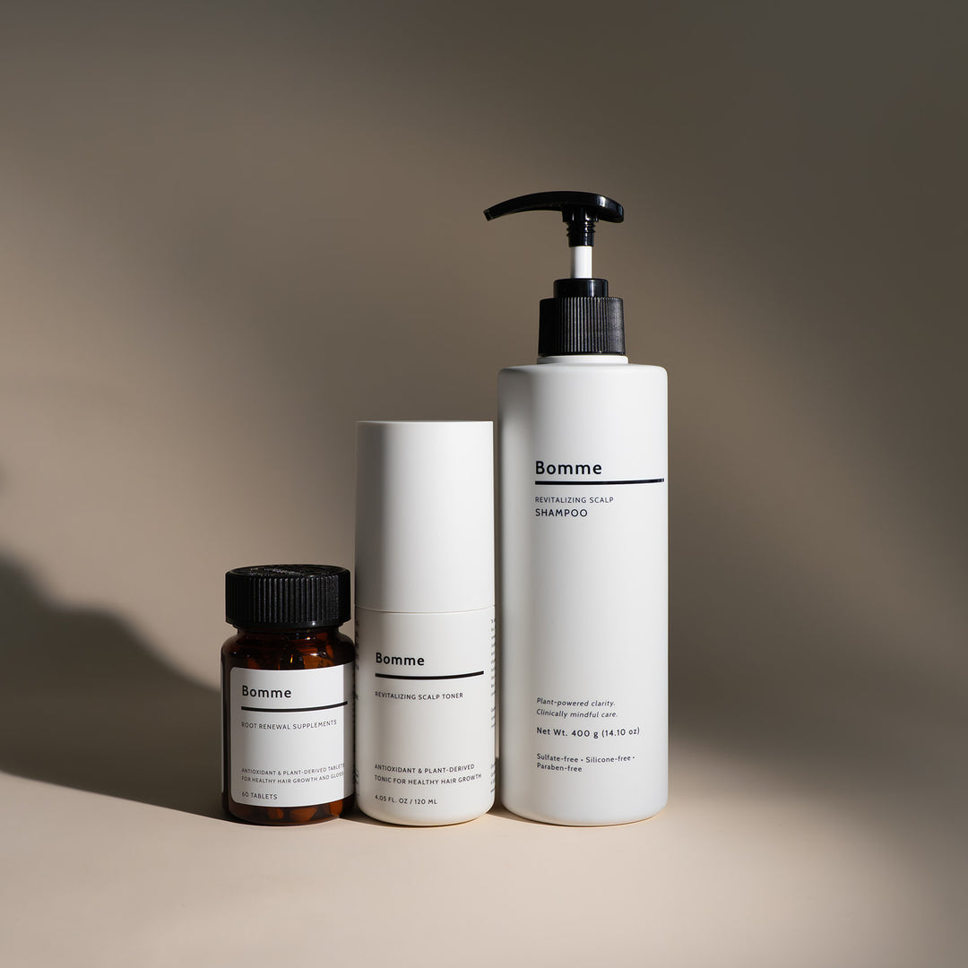 Bomme hair-care trio: Root Renewal Supplements, Revitalizing Scalp Toner, and Revitalizing Scalp Shampoo on a beige background with soft shadow.