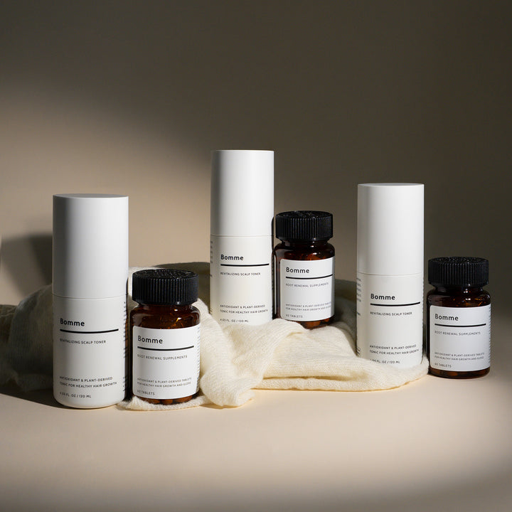 Bomme Essentials Set featuring a three-month supply of Revitalizing Scalp Toner and Root Renewal Supplements, displayed with minimalist packaging on soft fabric.