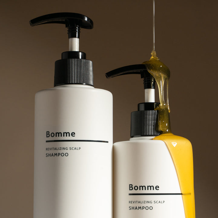 Bomme Revitalizing Scalp Shampoo bottles with pump dispensers, one shown with golden liquid highlight to emphasize antioxidant-rich formula.