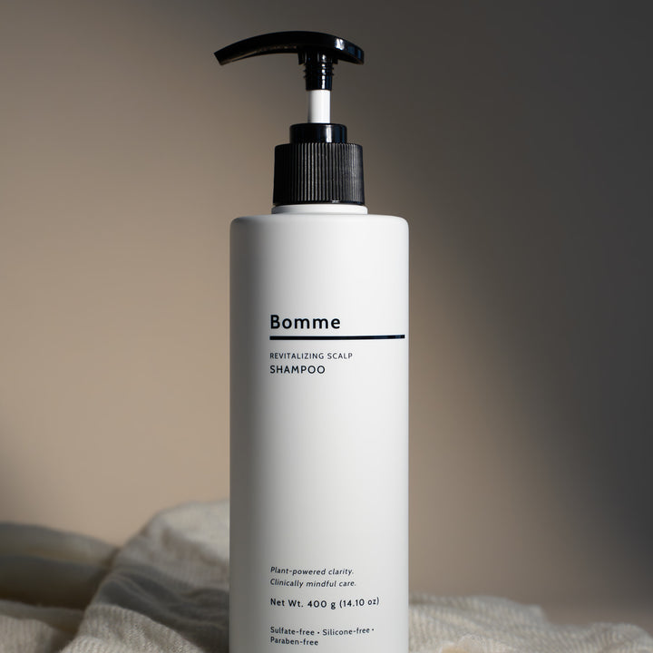 Bomme Revitalizing Scalp Shampoo with minimalist design, shown on fabric backdrop, clean plant-based scalp care