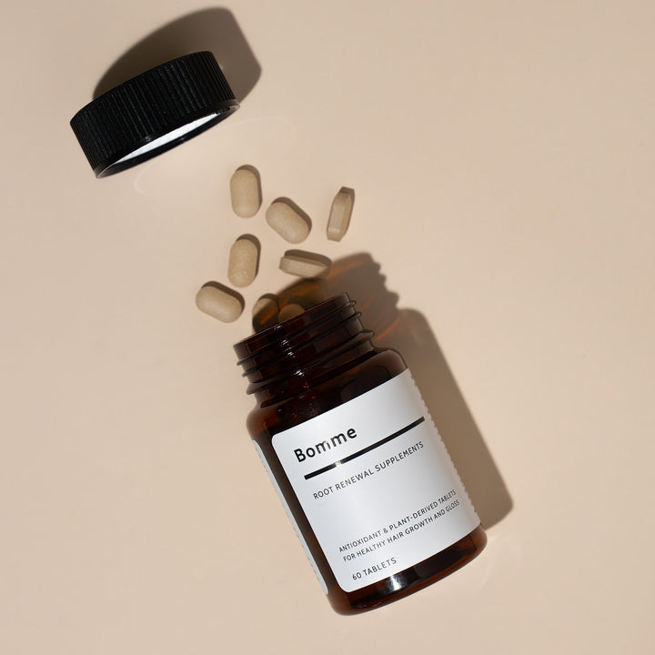 Bomme Root Renewal Supplements bottle tilted on its side with cap off and tablets spilling out.