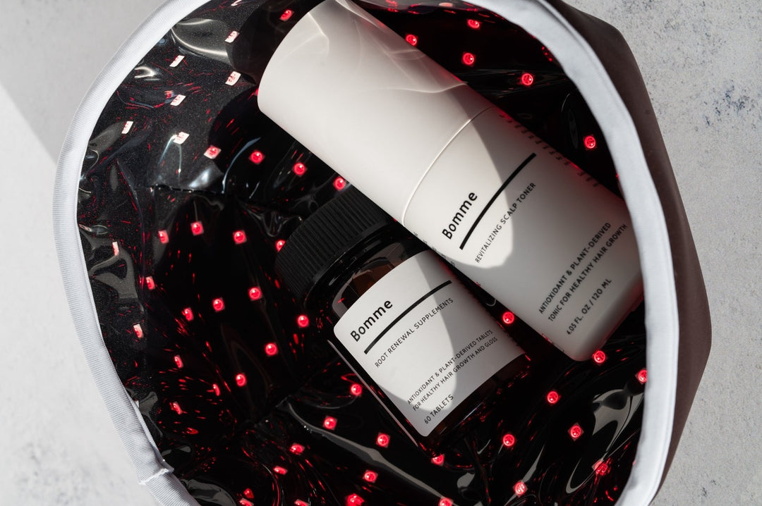 Bomme LED Red Light Therapy Hat with Root Renewal Supplements and Scalp Toner inside, surrounded by glowing red LEDs