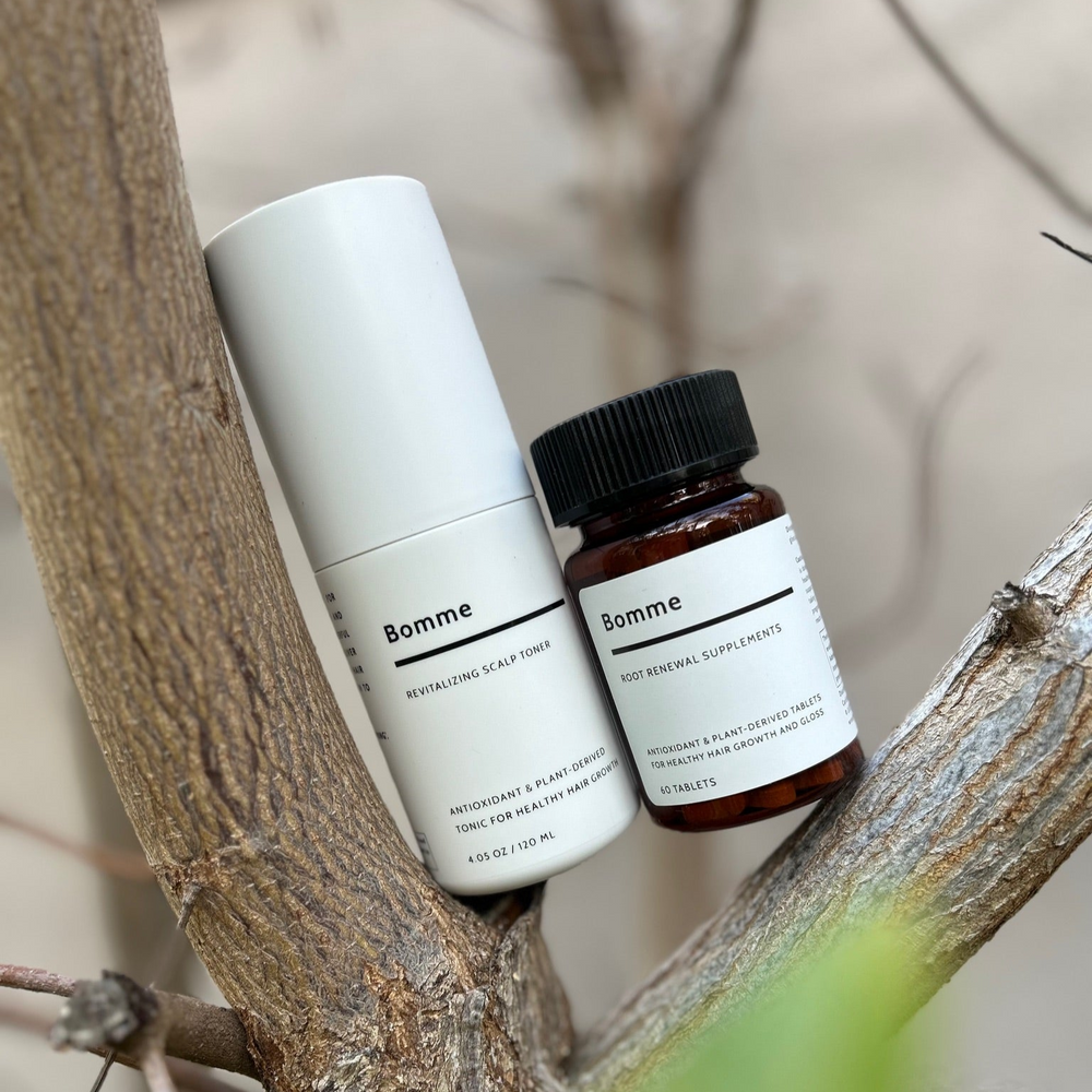 Bomme Root Renewal Supplement and Revitalizing Scalp Toner styled naturally among tree branches.