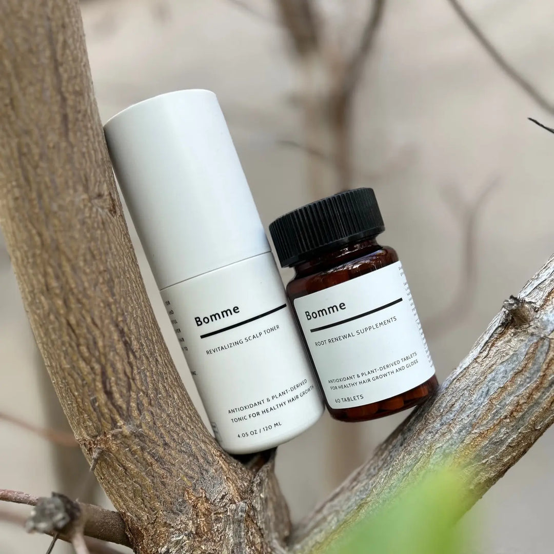 Bomme Root Renewal Supplement and Revitalizing Scalp Toner styled naturally among tree branches.