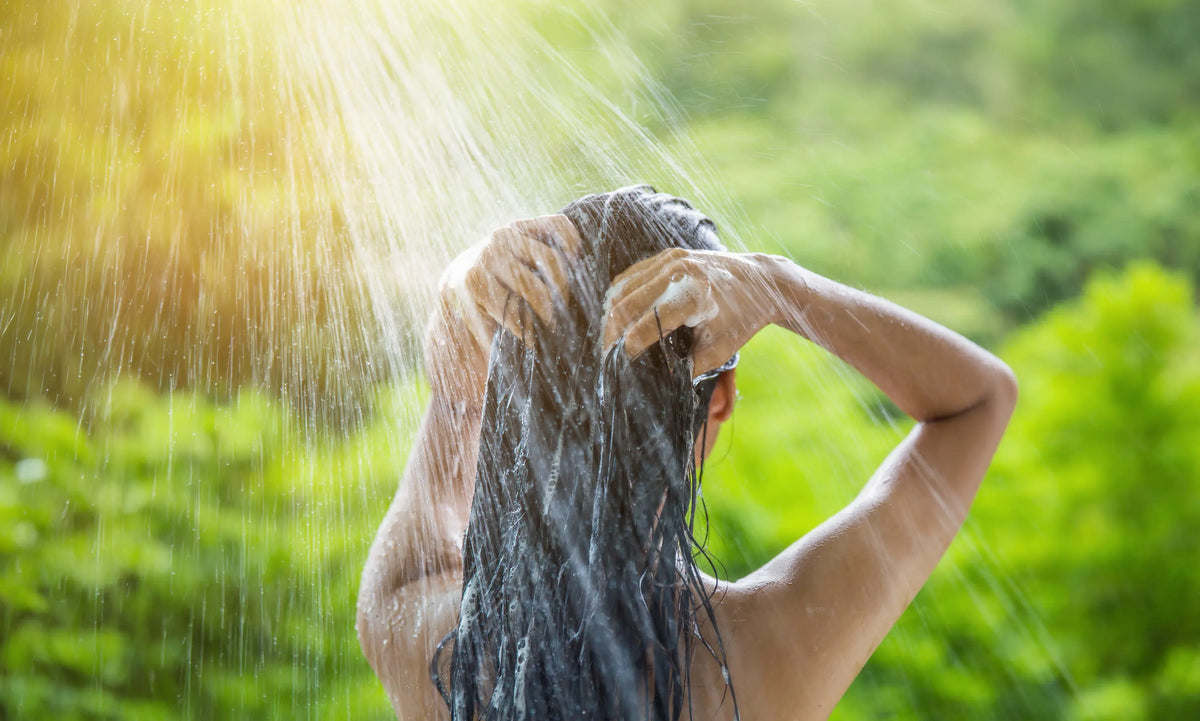 Close-up of hands lathering shampoo and massaging the scalp during a scalp treatment routine.